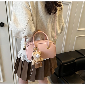 Pink crossbody square bag with gold hardware and cute bear charm shown on model
