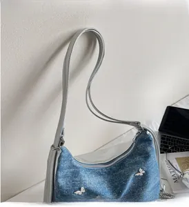 Détail du sac bandoulière en jean avec breloques papillons argentés et poignées solides
