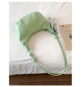 Detail of mint green pleated crescent bag with star charm and soft knotted strap