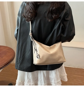 Minimalist beige underarm bag with silver heart charm shown on model in a chic indoor setting