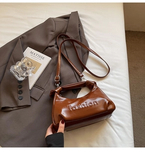 Detail of chocolate brown oiled leather bag featuring fashion embossing and a knotted handle