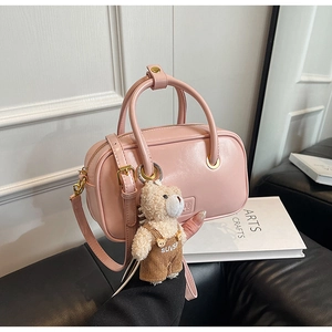 Detail of pink leather Boston bag with teddy bear pendant and gold metal hardware