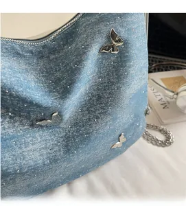 Vue détaillée du tissu denim bleu clair avec papillon argenté et strass brillants