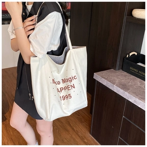 Detailed macro view of cream canvas tote bag with brown Make Magic HAPPEN printed text