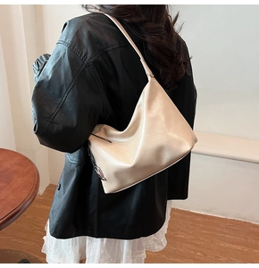 Detail of a minimalist cream PU leather underarm bag with pleated half-moon design