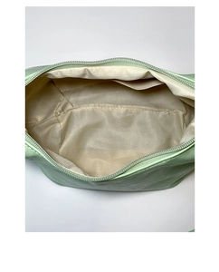 Detailed interior view of light green dumpling bag with cream fabric lining and inner pocket