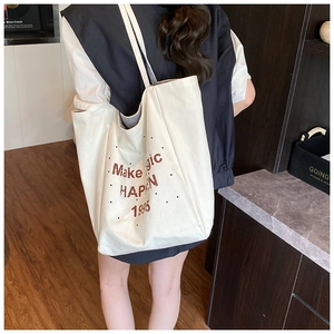 Detail shot of canvas tote bag with brown letter print and polka dot pattern shown from side