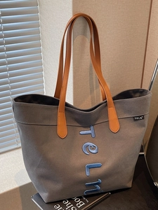 Large capacity grey canvas tote bag with brown leather handles and blue embroidery