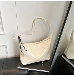 Close-up of cream PU leather underarm bag with silver heart pendant on a black book
