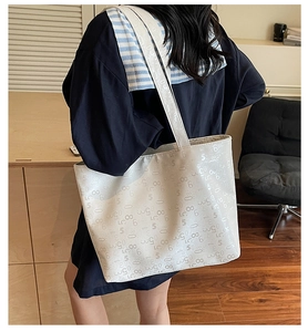 Close-up of cream white tote bag with reflective numeric patterns and glossy finish