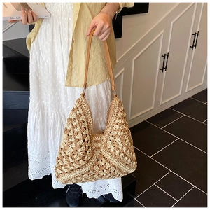 Detail of hollow-out hand-woven texture on the large straw tote bag with brown strap