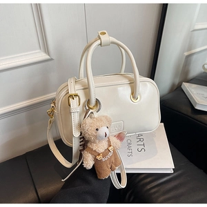 Detailed shot of white bowling bag with gold hardware and a cute teddy bear charm