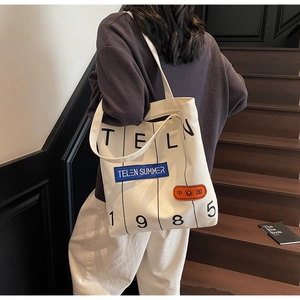 Detail of canvas tote bag with TELN 1985 print and vintage aesthetic patches