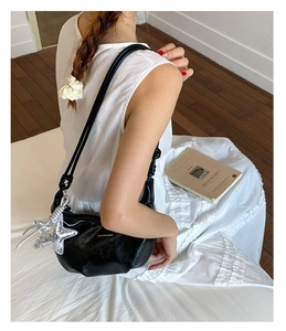 Close-up of black crescent hobo bag with a silver star pendant worn by a model
