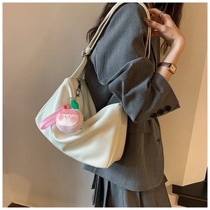 Detailed side view of white PU leather shoulder bag with peach plush charm and wide strap