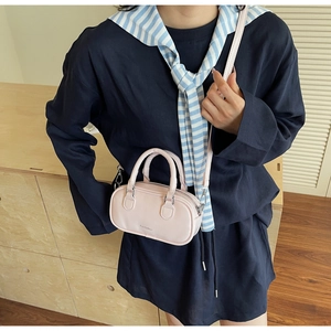 Detail shot of mini pink leather Boston bag with silver hardware on a crossbody model