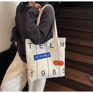 Close-up of cream canvas tote bag featuring vintage letters and colorful textile patches
