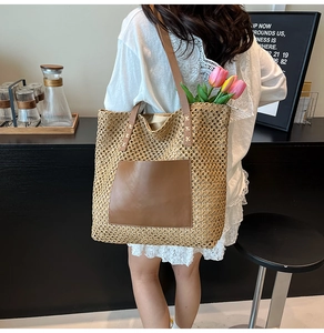 Close-up of a large straw tote bag with brown leather pocket and woven texture on a model