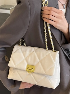 Sac bandoulière matelassé beige avec chaîne dorée porté par un mannequin