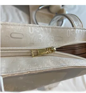 Detail of smooth metal zipper and embossed numbers on cream leather tote bag