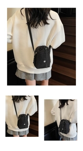 Détail du sac bandoulière noir en nylon avec cordon de serrage et écusson du logo