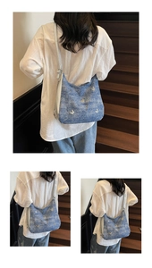 Détail de la broderie papillon blanc et de la chaîne en argent sur le sac en jean