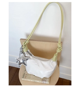 Detail of white dumpling bag with lime green strap and silver sequin star charm on a chair