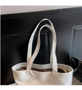 Macro shot of white tote bag featuring letter embossing and reinforced long shoulder straps