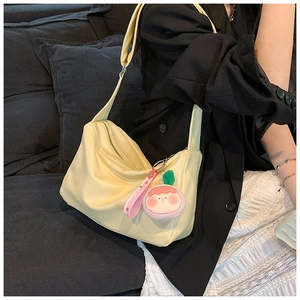 Detail of yellow minimalist hobo bag featuring pink strap and cute cartoon doll pendant