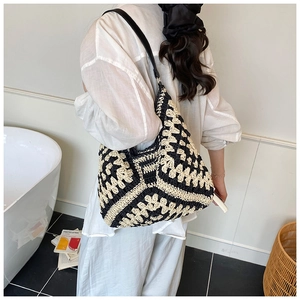 Detail of hand-woven black and white geometric crochet tote bag with sleek leather shoulder strap