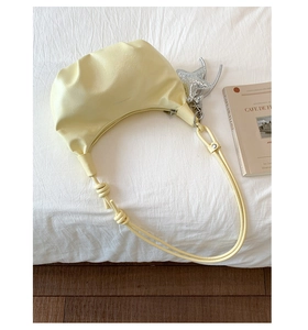 Detailed texture of creamy yellow pleated cloud bag with a silver star pendant