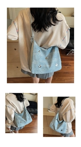 Détail du sac à épaule en denim bleu clair avec breloques papillons argentés et chaîne