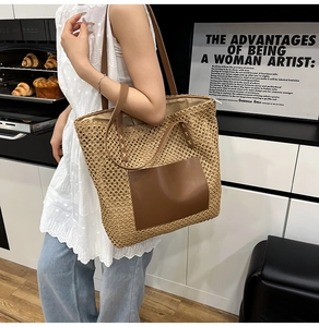 Detail of a large straw tote bag with brown leather handles and front pocket for beach