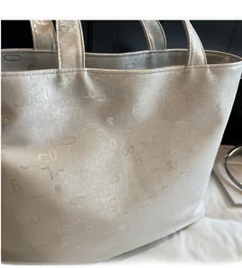 Close-up of cream white tote bag with embossed numbers and soft matte leather texture