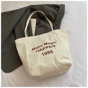 Detailed view of off-white canvas tote bag featuring vintage brown letter print textures