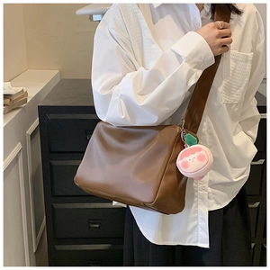 Detail view of brown PU leather shoulder bag with wide strap and pink peach charm