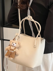 Minimalist beige lychee grain bucket bag with cute plush bear charm for daily wear