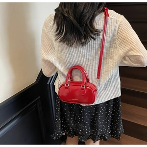 Detail view of a bright red patent leather Boston bag with shiny finish and silver hooks