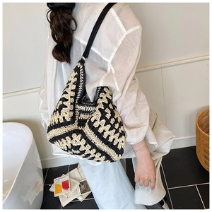 Close-up of black and white hand-woven tote bag featuring geometric floral patterns and thin strap