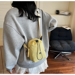 Bandoulière réglable et logo noir sur un sac bandoulière jaune en nylon avec cordon de serrage