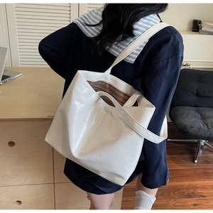 Detail of white crocodile pattern tote bag with spacious interior and brown lining
