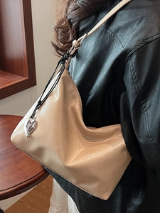 Minimalist beige underarm bag in soft matte leather with a silver heart metal charm