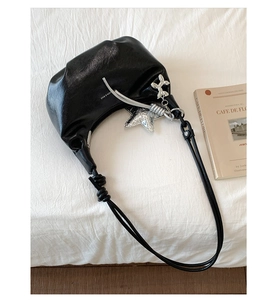 Detail of black patent leather crescent bag with silver star and balloon dog charms
