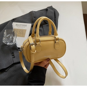 Detail of yellow oval Boston handbag with silver hardware and adjustable shoulder strap