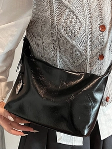 Chic black polished leather underarm bag with a silver heart pendant and hobo style