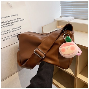 Detail of soft brown PU leather tote bag with wide strap and cute peach plush charm
