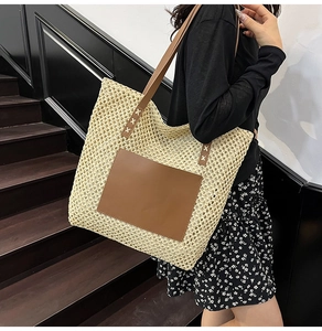 Detail of cream woven tote bag with brown leather patch and shoulder straps in a macro view