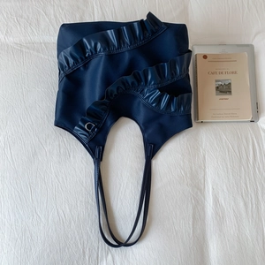 Detailansicht der marineblauen Schultertasche mit mehrlagigen Rüschen und Metallring-Detail