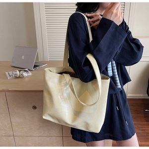 Detail view of beige tote bag with crocodile pattern and long shoulder handles