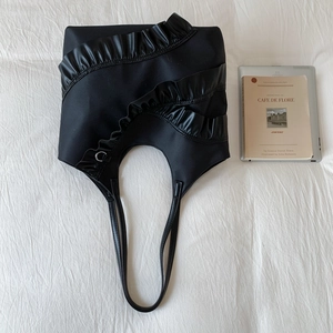 Detailaufnahme der schwarzen Tragetasche mit eleganten Rüschen und gewellten Lederakzenten
